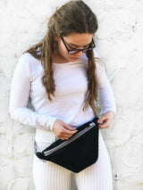 Women wearing black urban belt bag which has zipper pocket, black fanny pack is on her